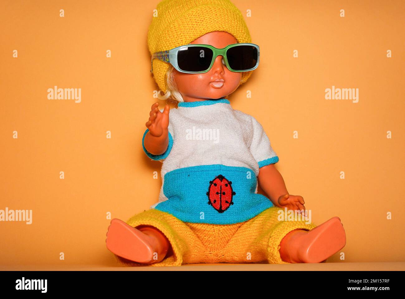 Smart doll with sunglasses and yellow knitted cap, children's toy from the GDR of the 1970s, concept of childlike play and human expression. Stock Photo