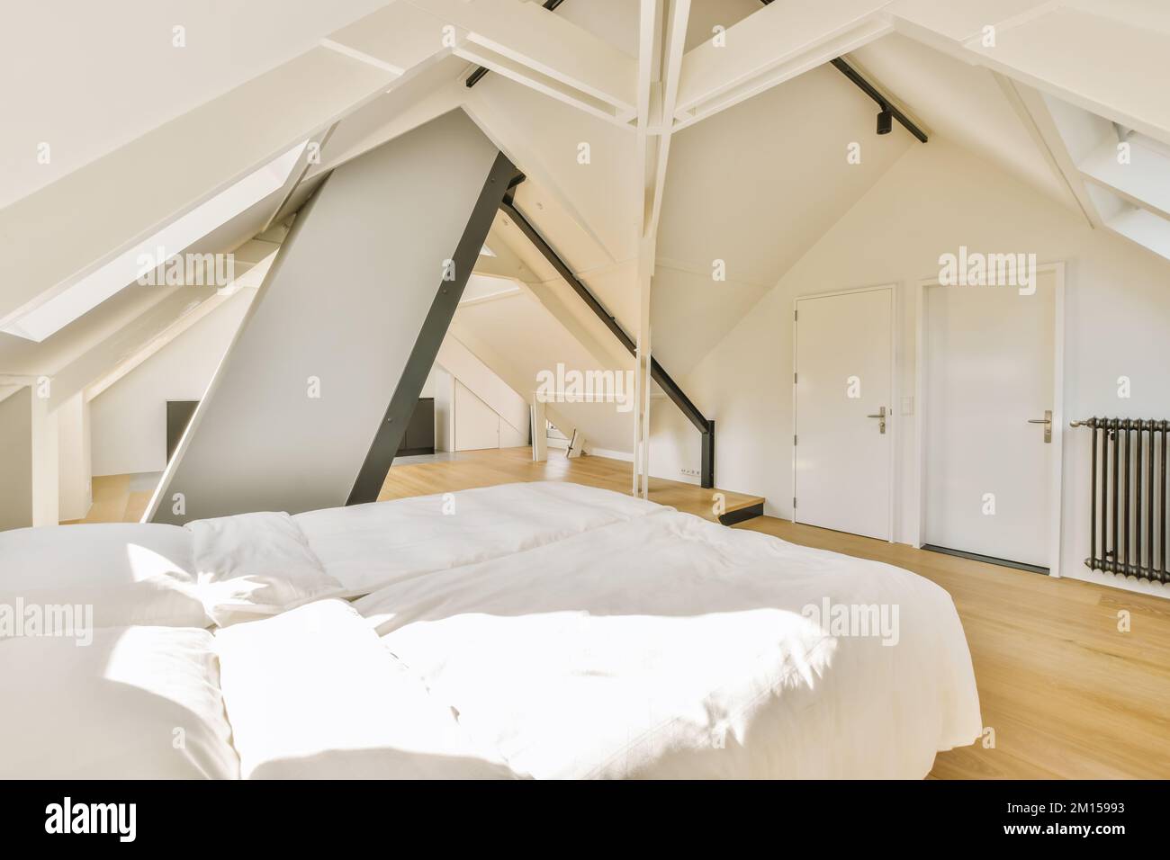 a bed in a bedroom with white sheets and pillows on top of the bed is an attic - style loft Stock Photo