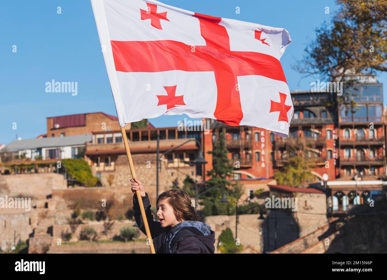 Tbilisi, Georgia - November 13, 2022: a boy holds the national flag of Georgia, fluttering in the wind. Stock Photo