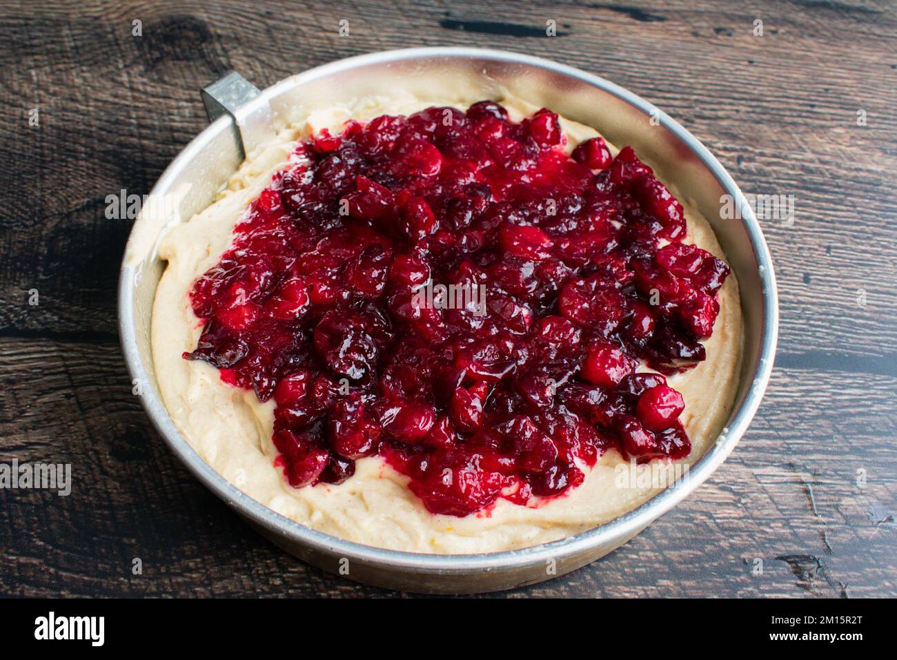 Spiced Cake Batter Topped with Cranberry Sauce in a Round Cake Pan