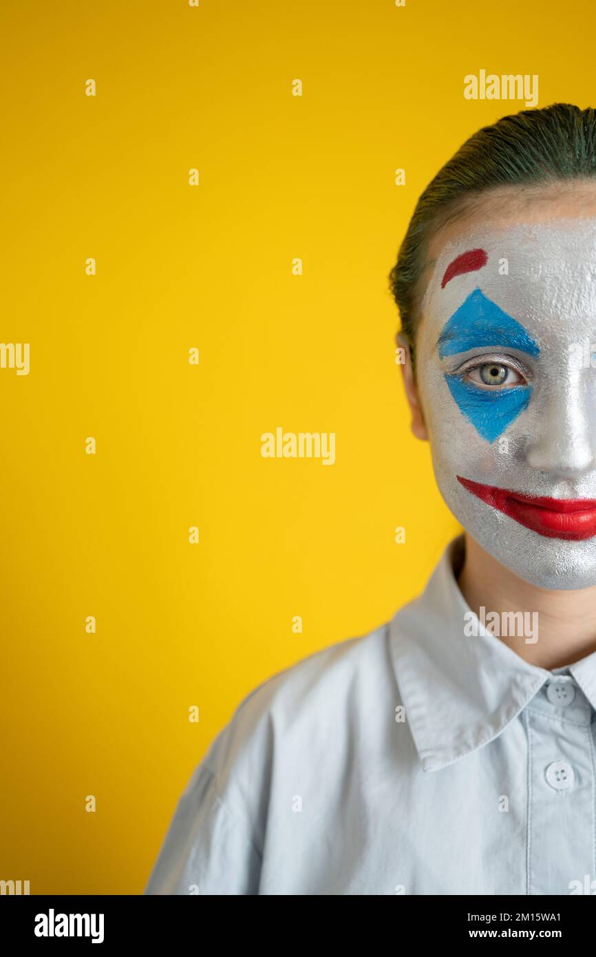 Crop kid with green hair and colorful makeup in white shirt looking at