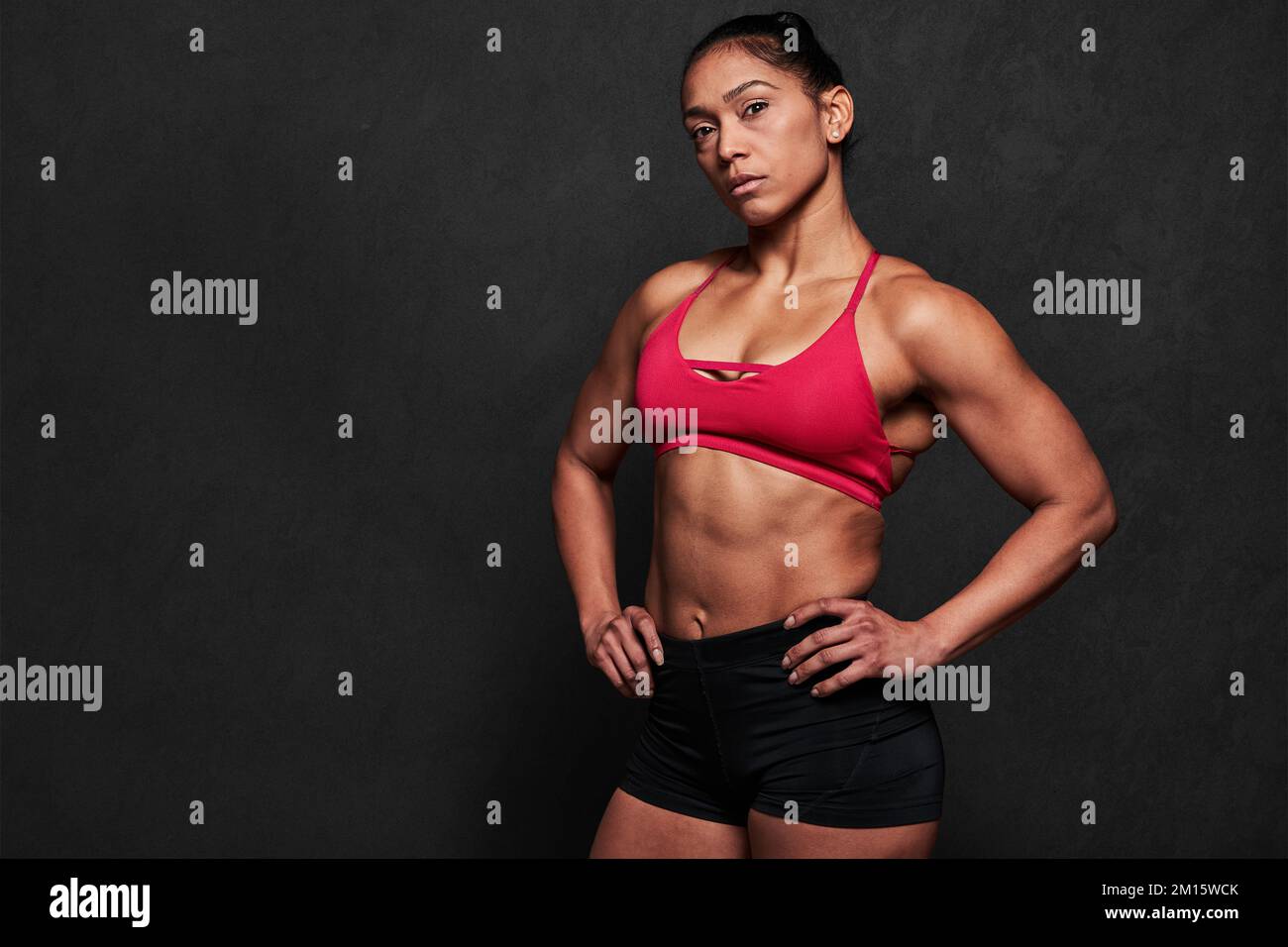 Back view of unrecognizable strong female with perfect sportive body  wearing red top and shorts standing on black background Stock Photo - Alamy