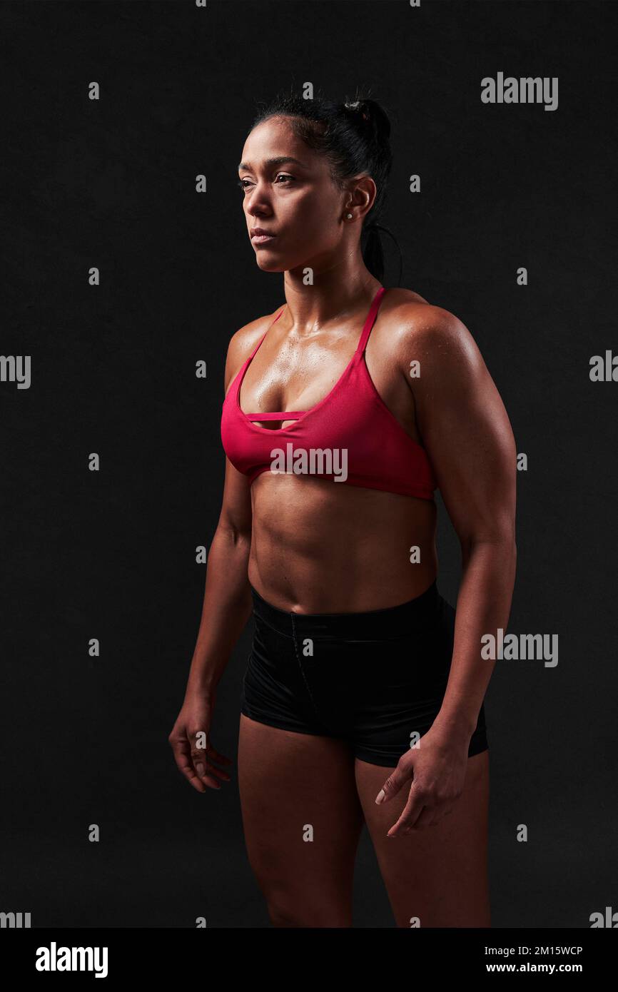 Back view of unrecognizable strong female with perfect sportive body  wearing red top and shorts standing on black background Stock Photo - Alamy