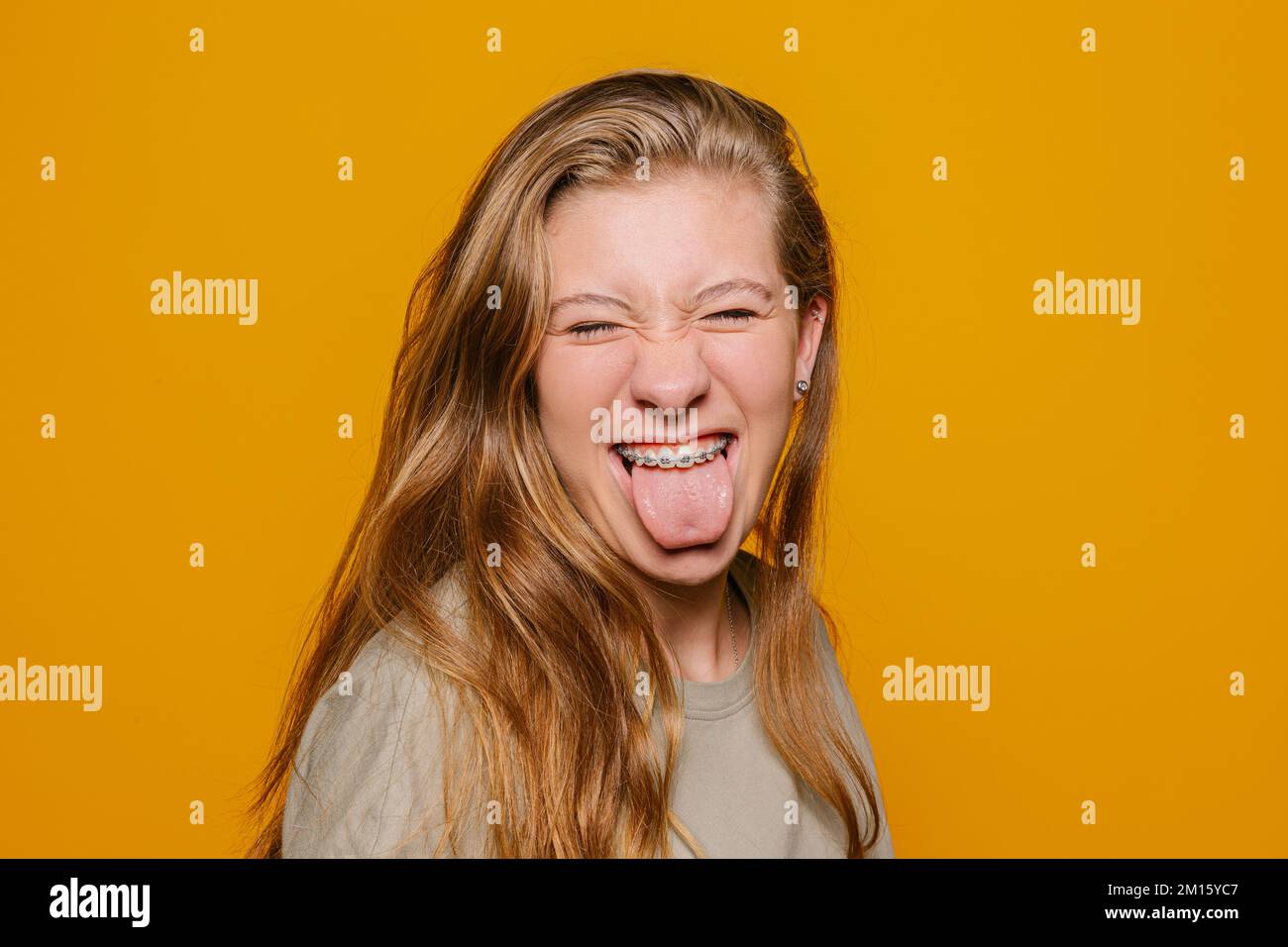 Pretty young teen with brackets sticking out tongue and looking at