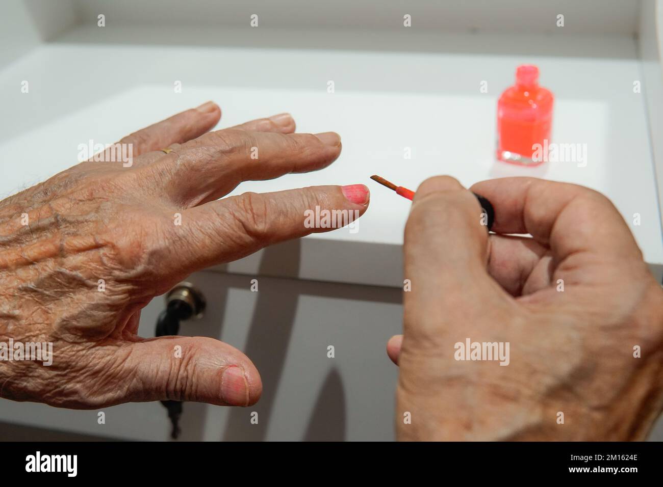 hands of an old man painting his nails red. hands of an old man