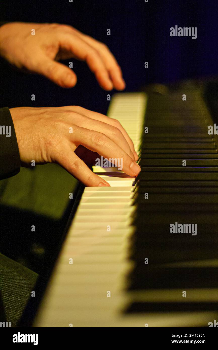 Closeup of the keys of a played piano in moody yellow stage light