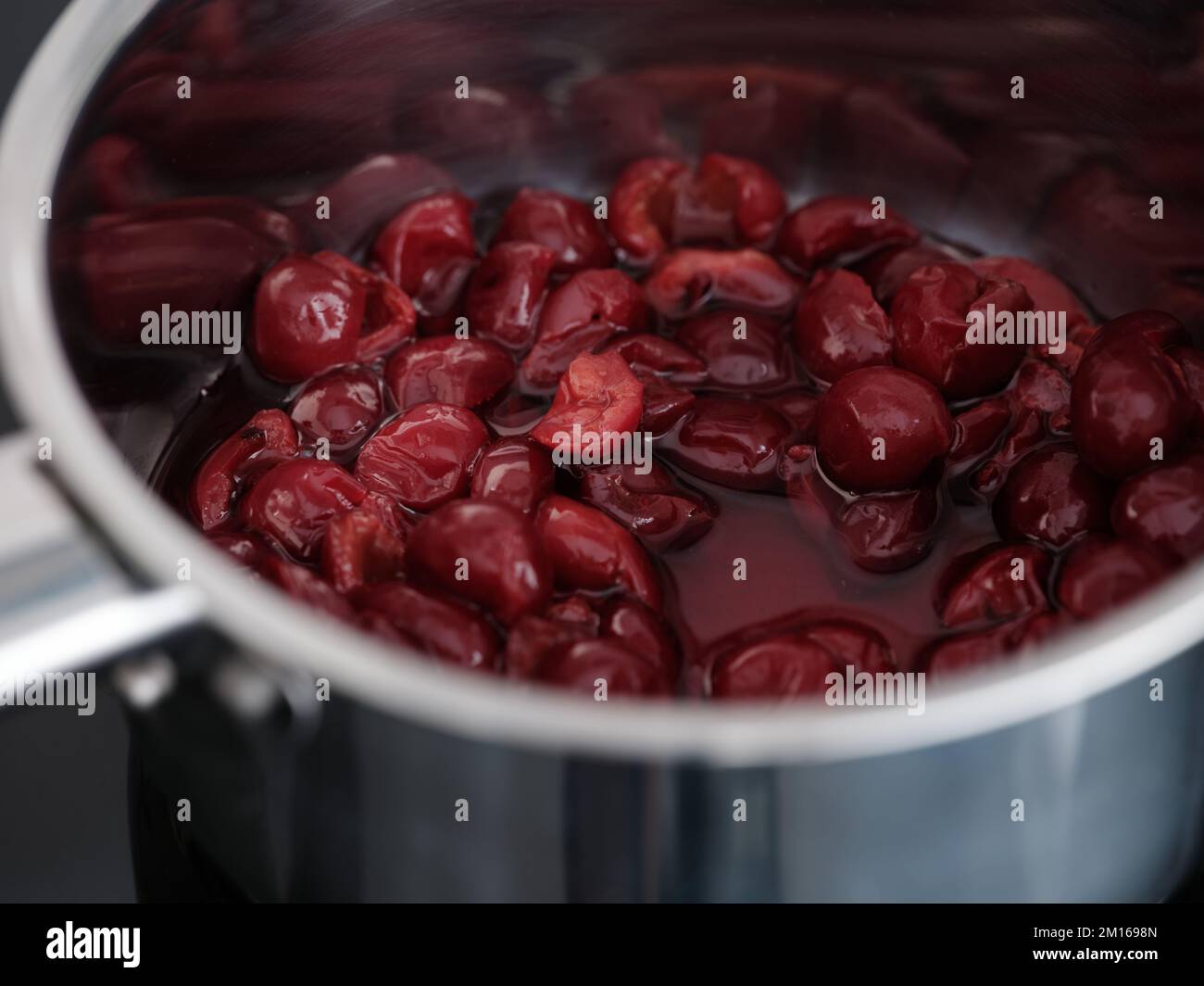 A pot with pitted red cherries in it ready to be made in to jam. Close up. Stock Photo