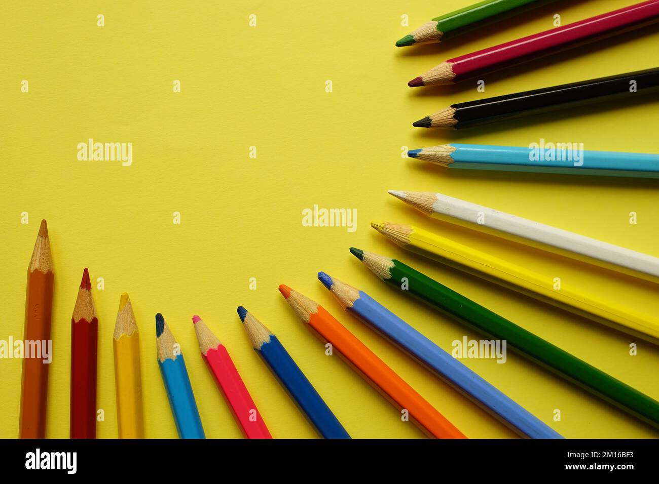 a set of colored pencils on a yellow table. Stock Photo