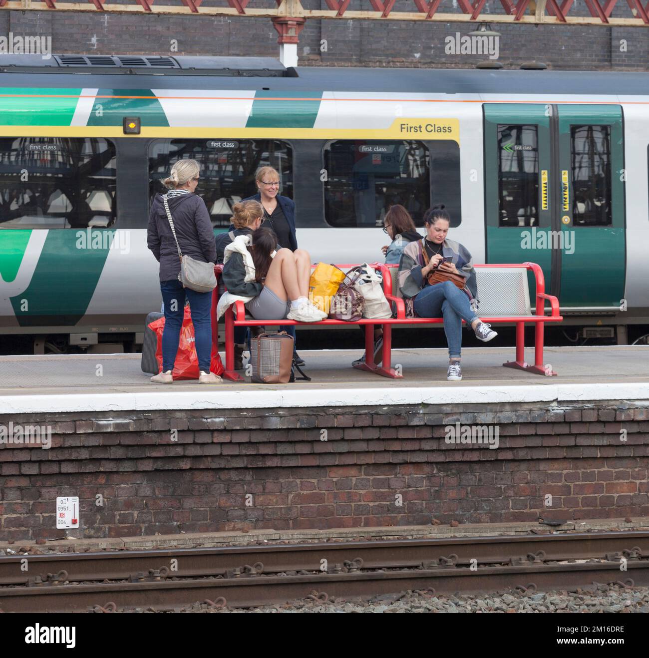 Rail passengers waiting in front of a London North Western Railway train at Crewe railway