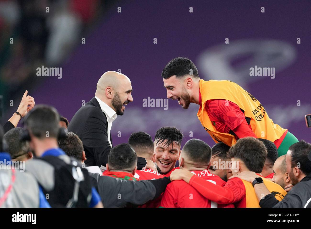Doha, Qatar. 10th Dec, 2022. Morocco's head coach Walid Regragui (top L) celebrates with players after winning the Quarterfinal between Morocco and Portugal of the 2022 FIFA World Cup at Al Thumama Stadium in Doha, Qatar, Dec. 10, 2022. Credit: Xiao Yijiu/Xinhua/Alamy Live News Stock Photo