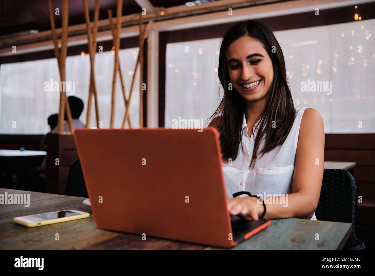 Smiley businesswoman working with a laptop in a cafeteria Stock Photo