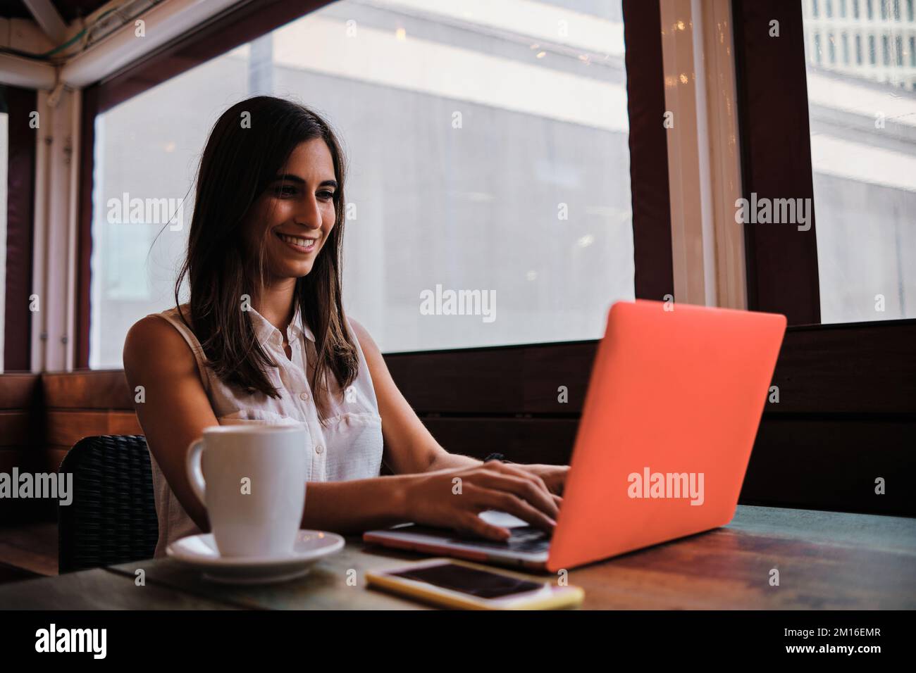 Woman working with a laptop sitting in a cafeteria Stock Photo