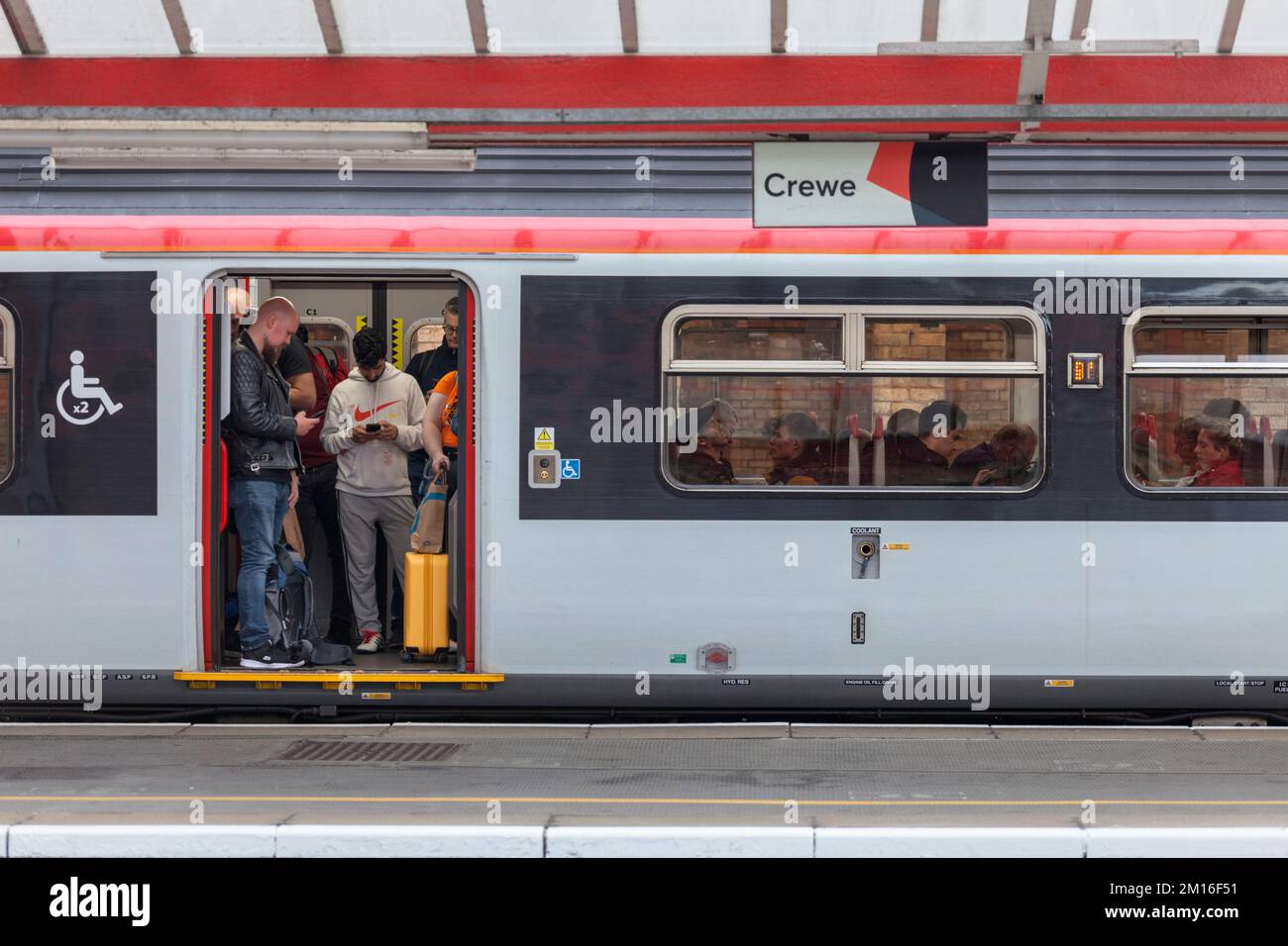 Full and standing crowded Transport For Wales passenger train at Crewe station on the west coast mainline, UK Stock Photo