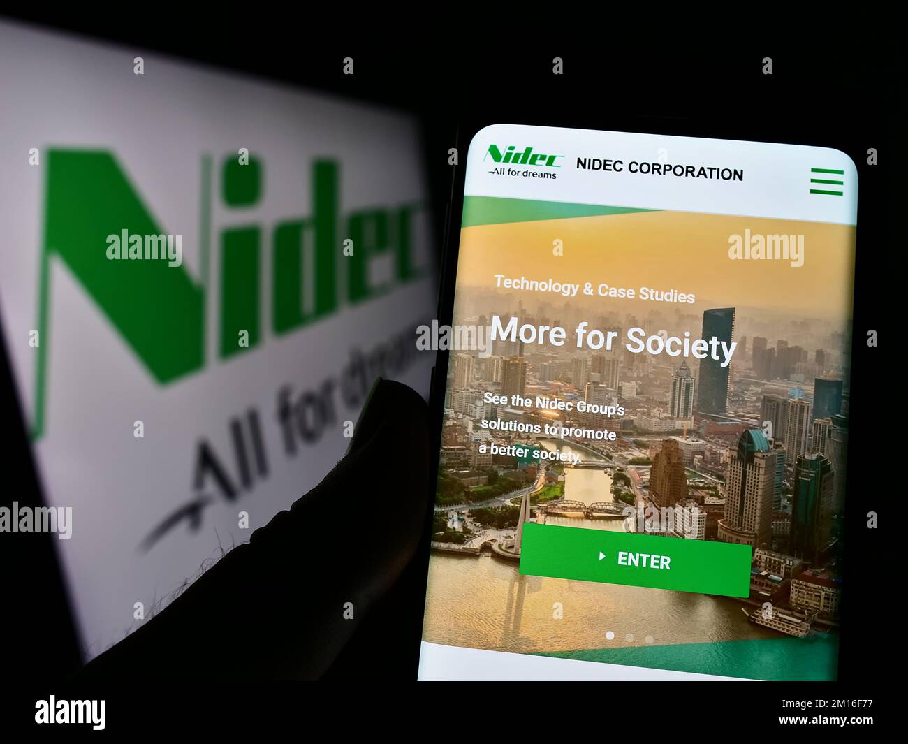 Person holding smartphone with website of Japanese motor company Nidec ...