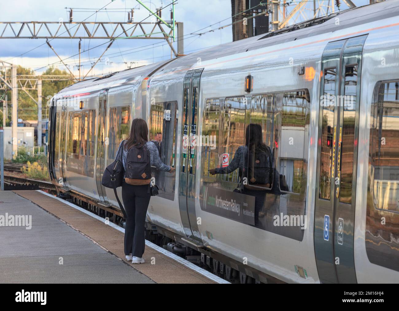 Lone passenger boarding a London North Western Railway train at Crewe with a reflection in the