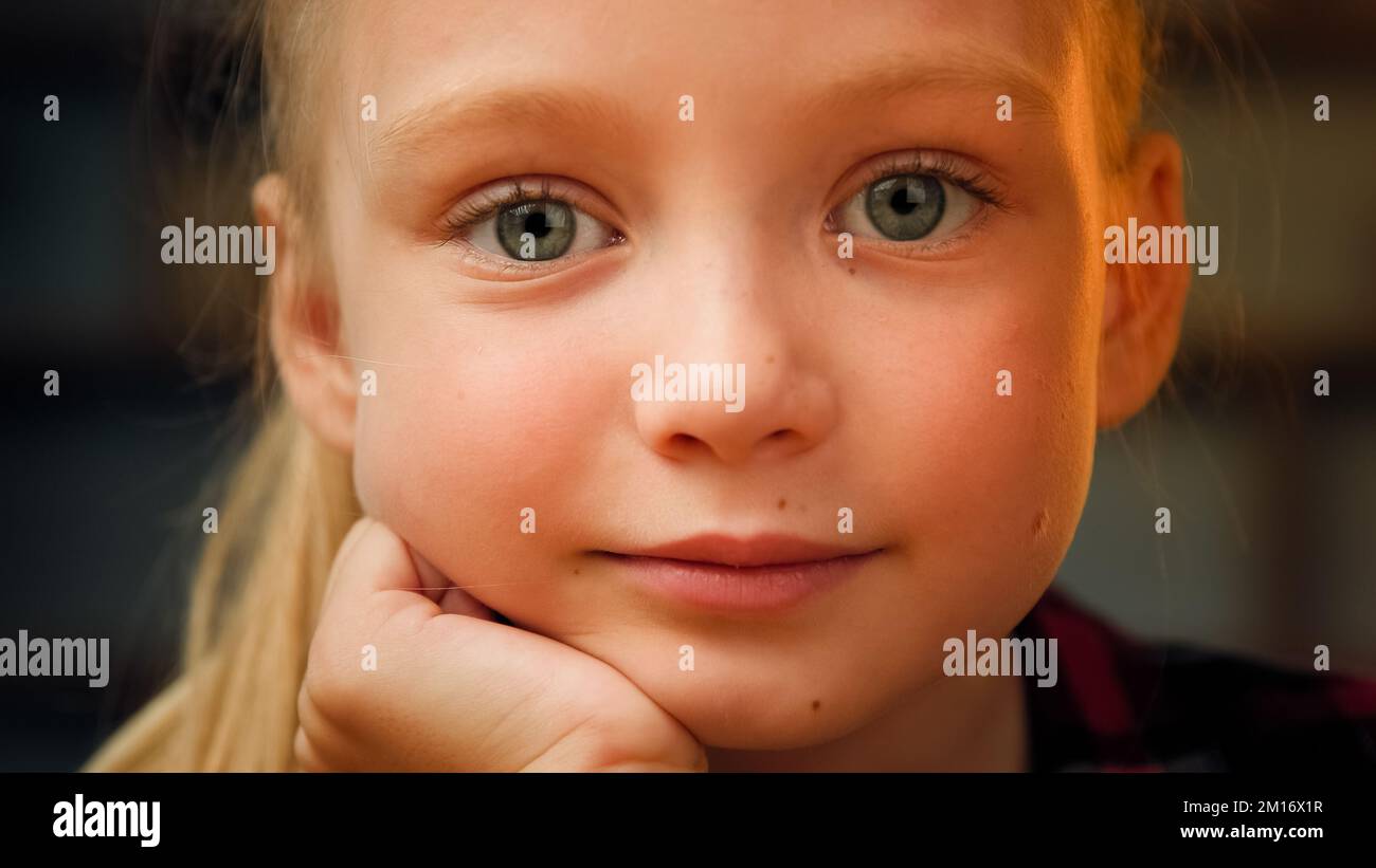 Close up portrait little cute daughter angelic blonde girl with big green eyes beautiful caucasian kid preschooler adorable small model looking at cam Stock Photo