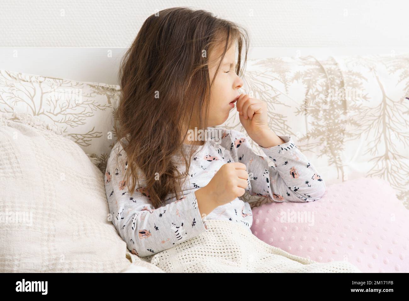 Poor, unfortunate little preschooler child, girl in pajamas coughing, lying in soft bed