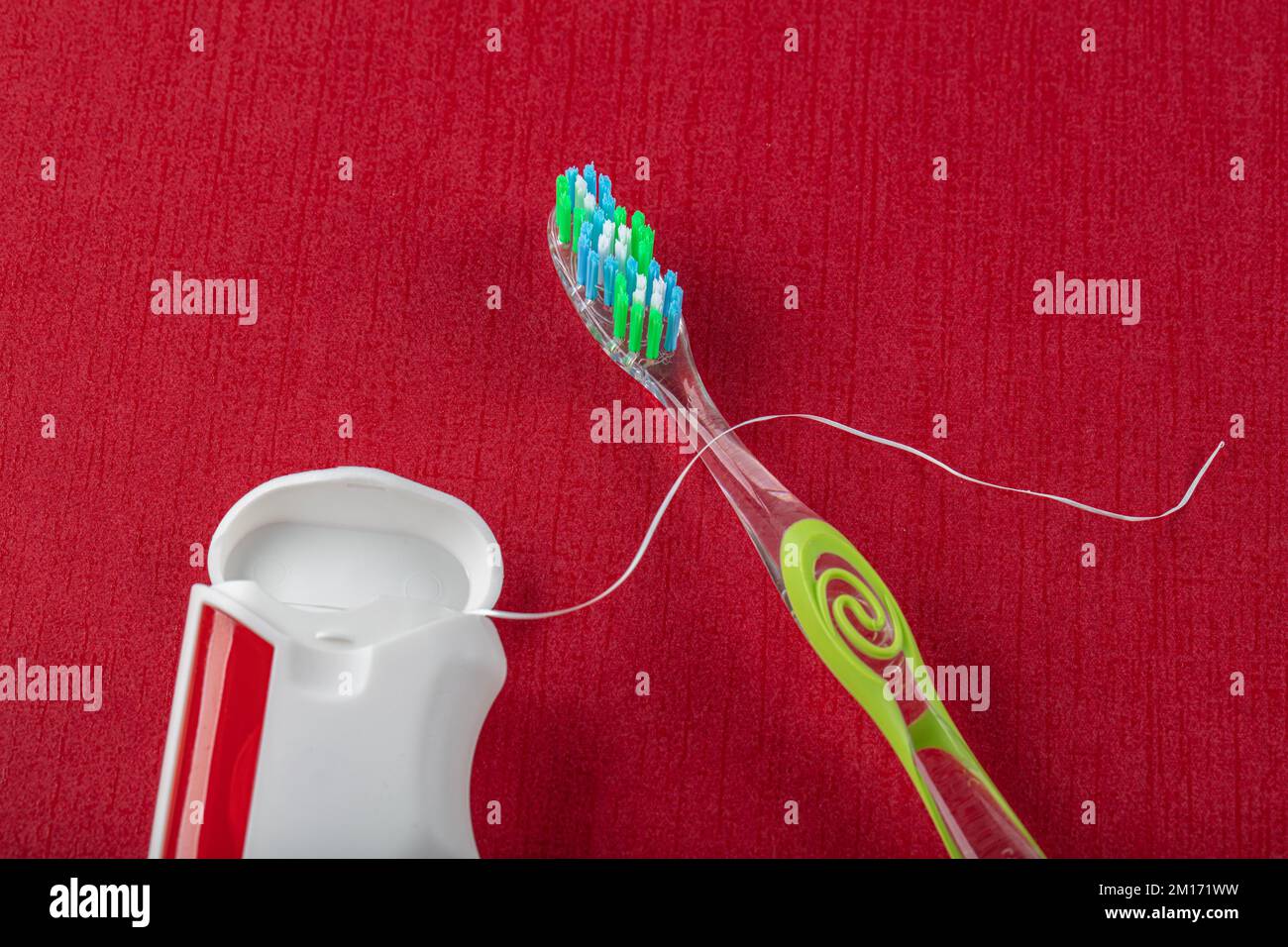 Dental floss and toothbrushes on red background. Care of teeth health