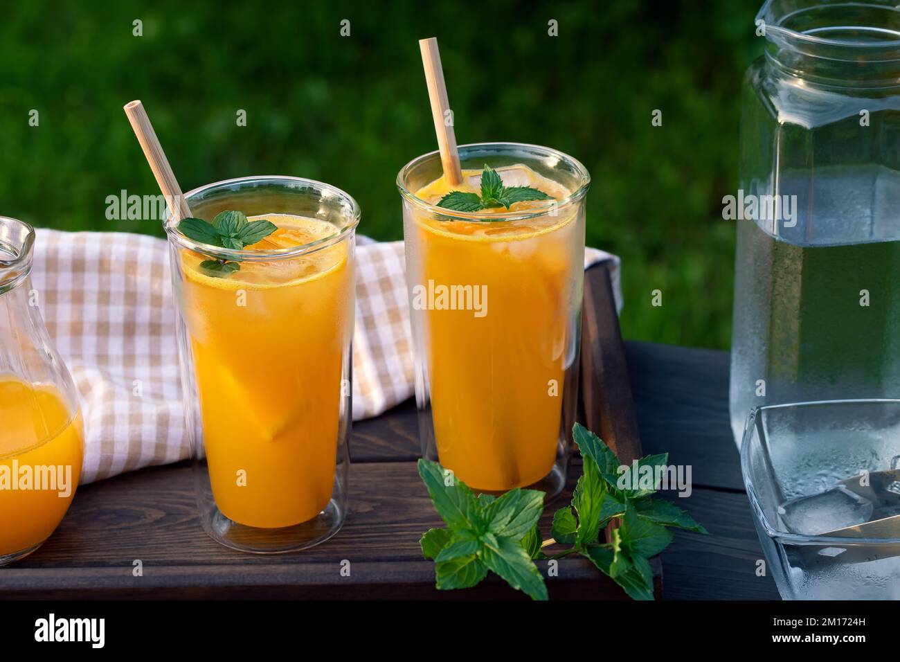 Refreshing summer homemade orange cocktail in tall double glass glasses with mint and ice, selective focus. Stock Photo