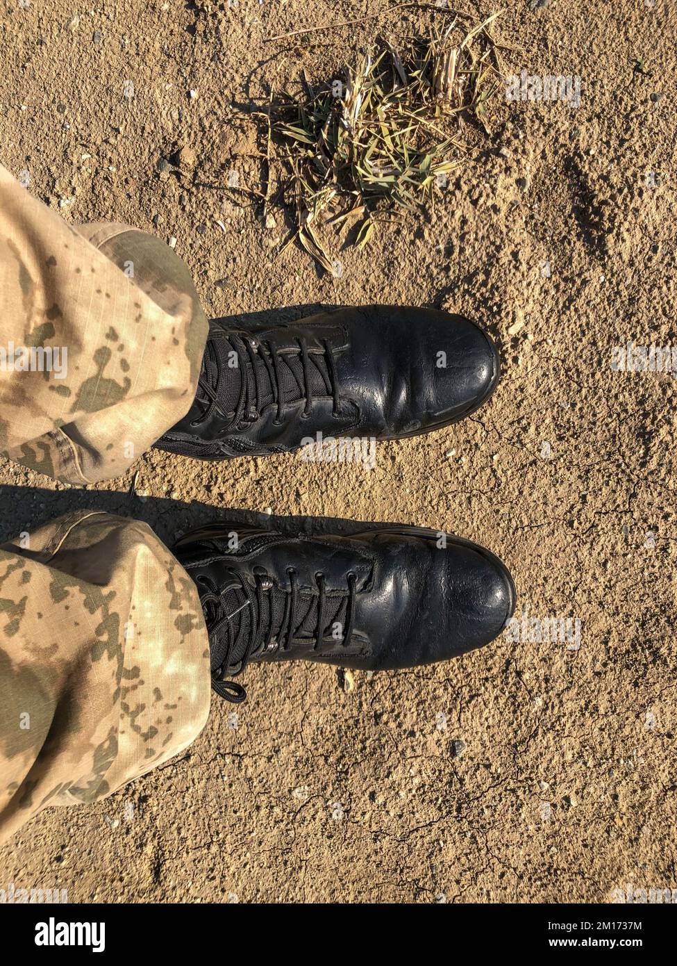 Soldier boots, soldier is standing with black boots on the ground, selective focus. Stock Photo