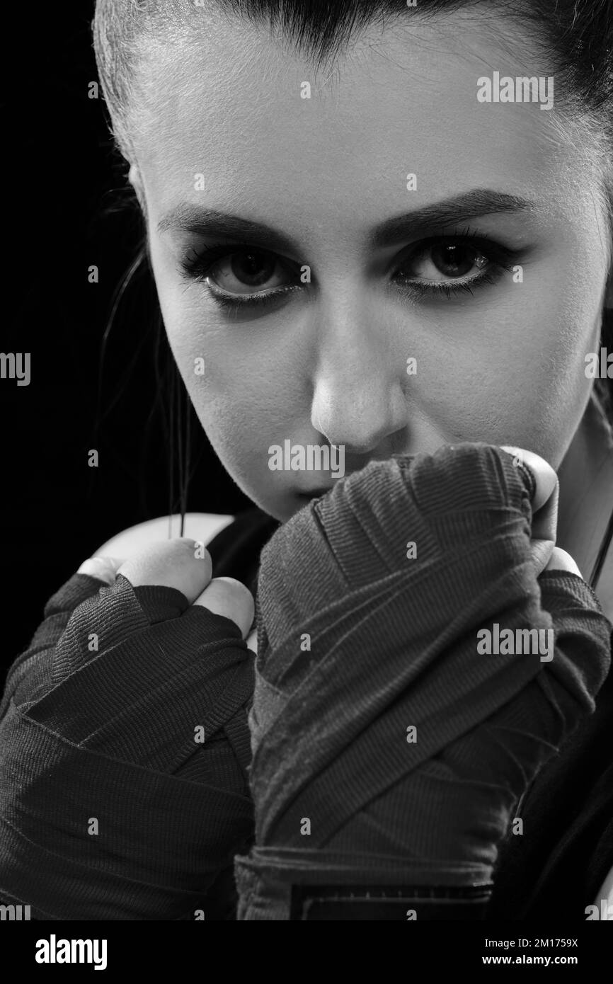 Muay Thai female boxer in attack pose. Fitness young woman boxing training on black background monochrome Stock Photo