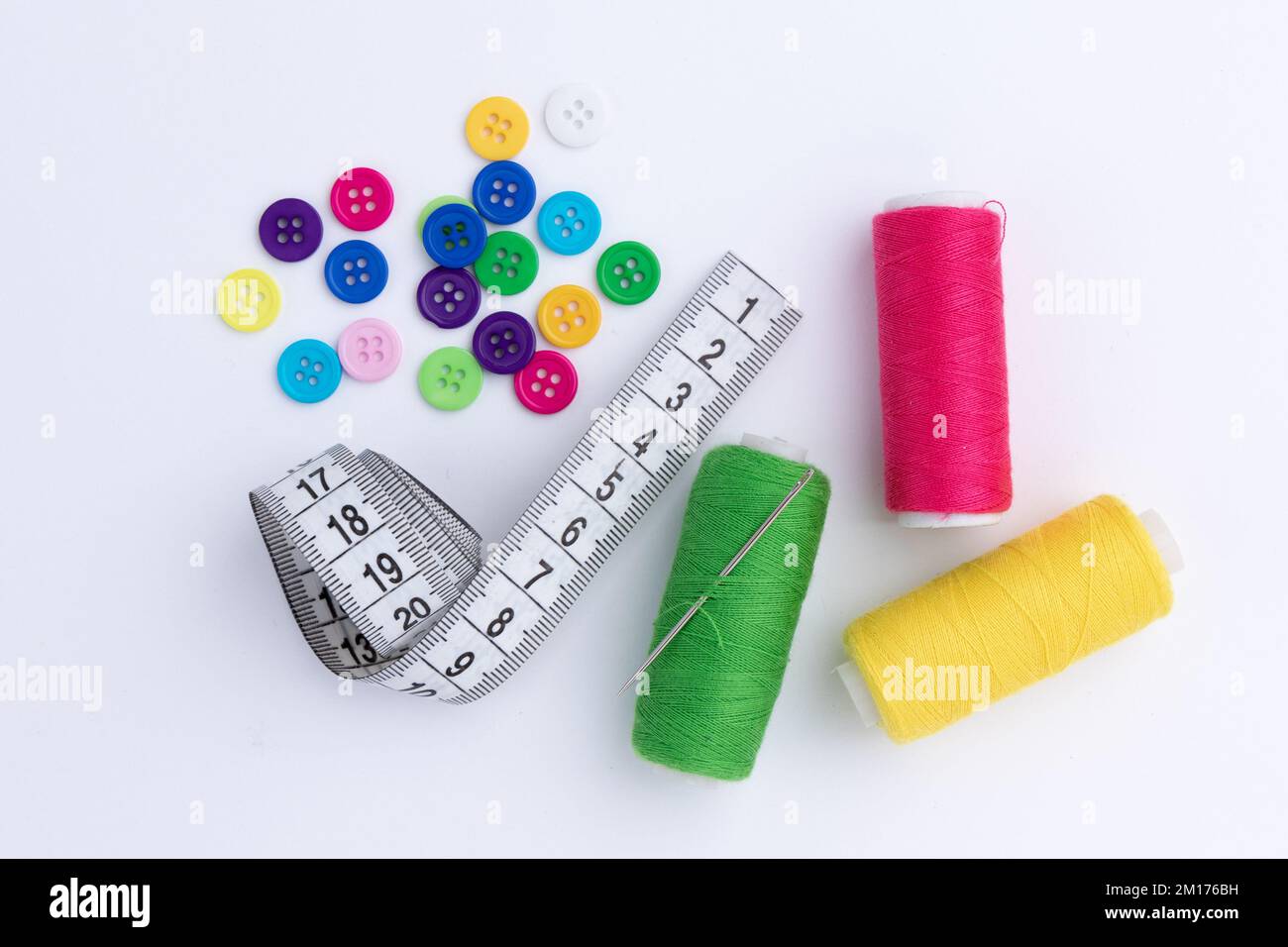 colored thread coils, pins and tape measure on white background, sewing