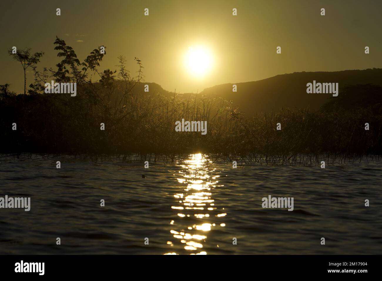 View as the sun rises in Suchitlan lake in Suchitoto.. The Suchitlan Lake is El Salvador's largest lake stretching over 134 kilometers across four regions of Chalatenango, Cabañas, Cuscatlan, and San Salvador. Stock Photo