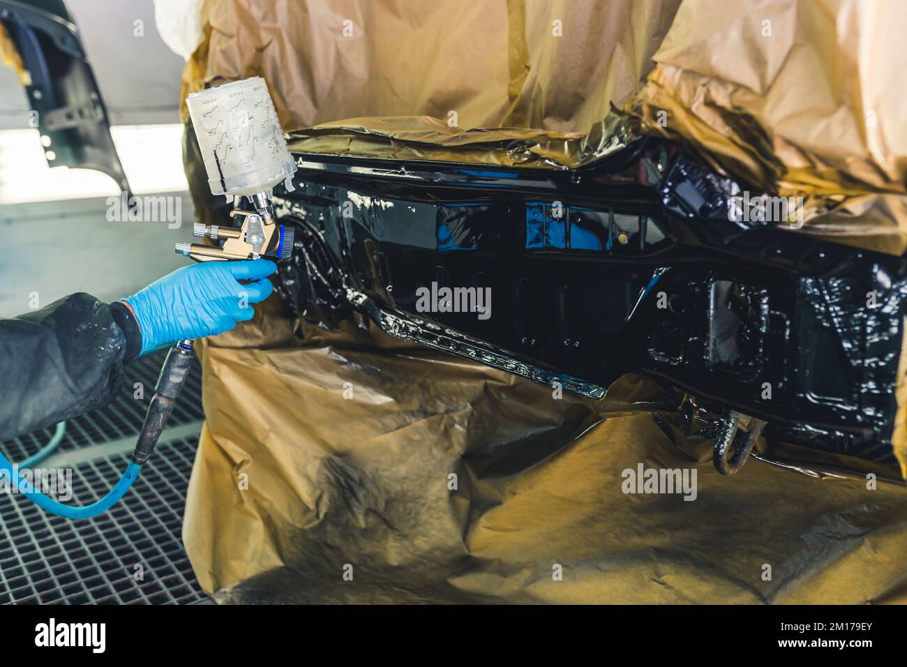 Car detailing concept. Inside the paint spray booth. Hand in blue