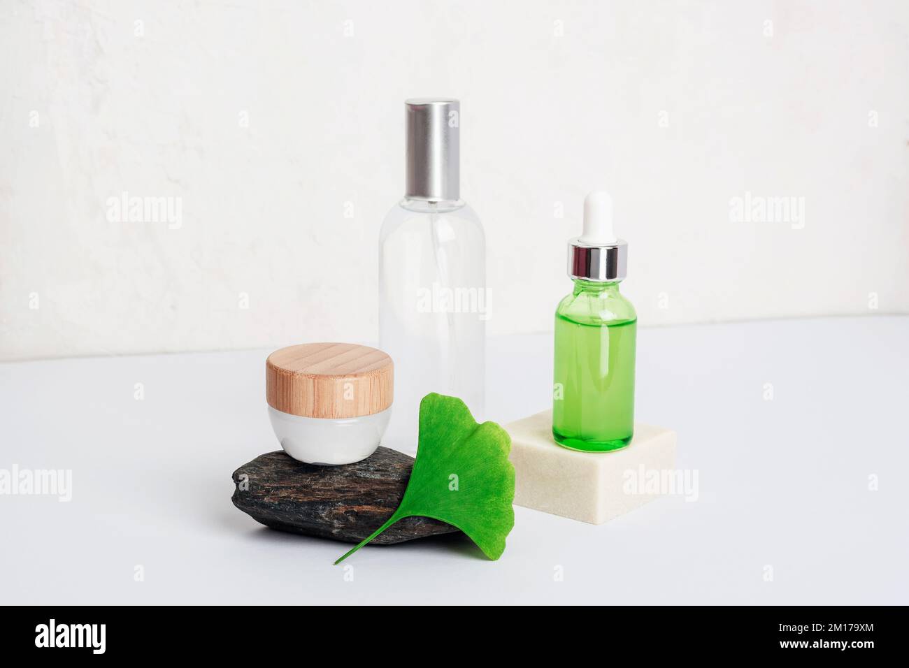 Fresh green ginkgo biloba leaf, cosmetic serum and tonic bottles, cream jar on white table. Natural cosmetics concept. Closeup. Stock Photo