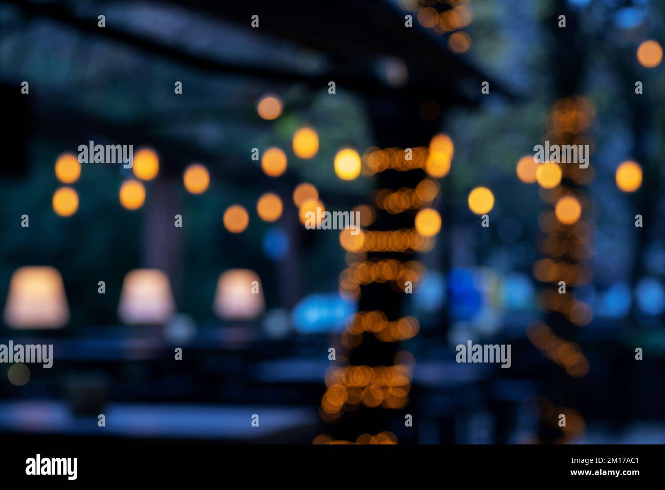 Street cafe at night blurred background with bokeh lights. Stock Photo