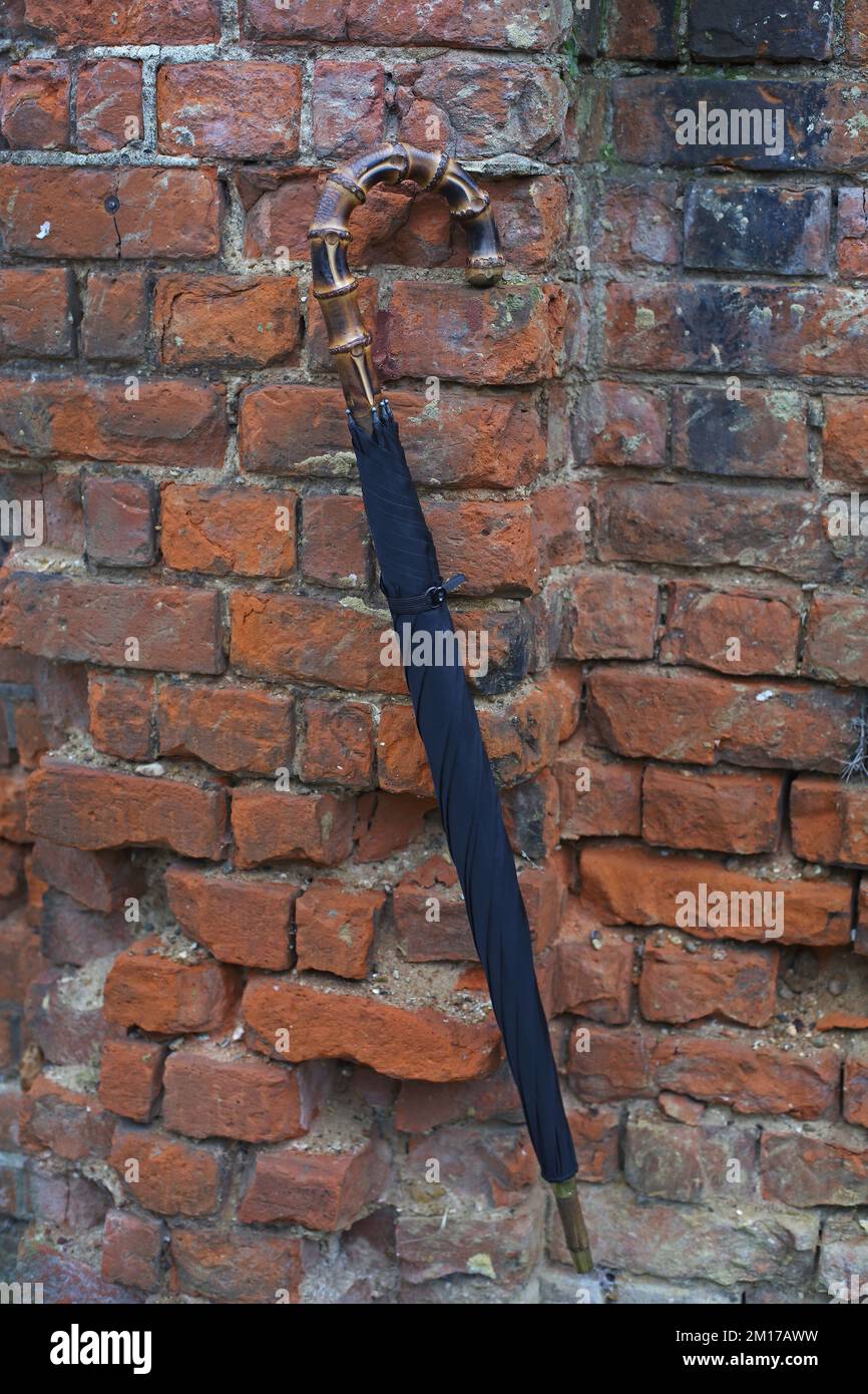 Closed umbrella haning on brick wall Stock Photo