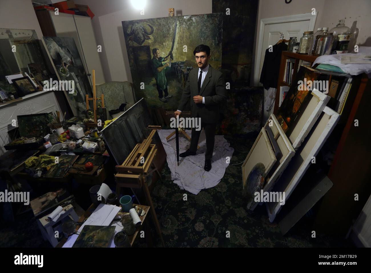 painter standing with umbrella in his studio. Stock Photo