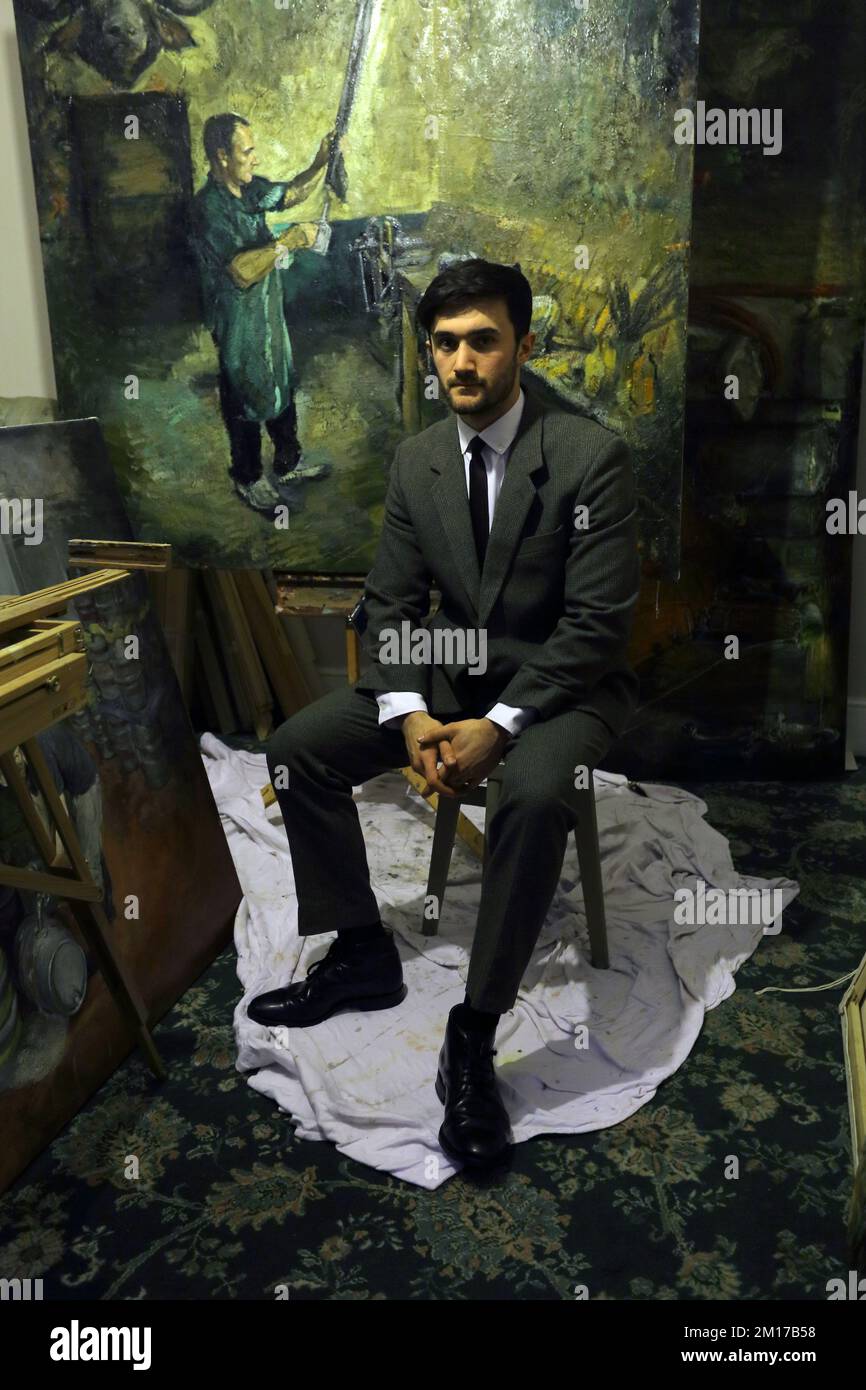 Portrait of a painter artist who works in his studio. Portrait of a painter with oil painting  in his studio. Stock Photo