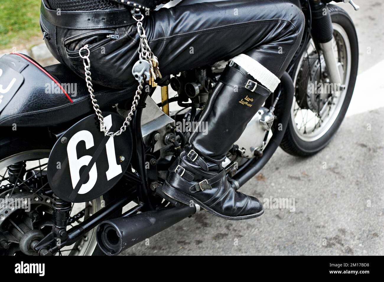 British rocker in black leather gear wearing boots on classic british motorcycle . Stock Photo