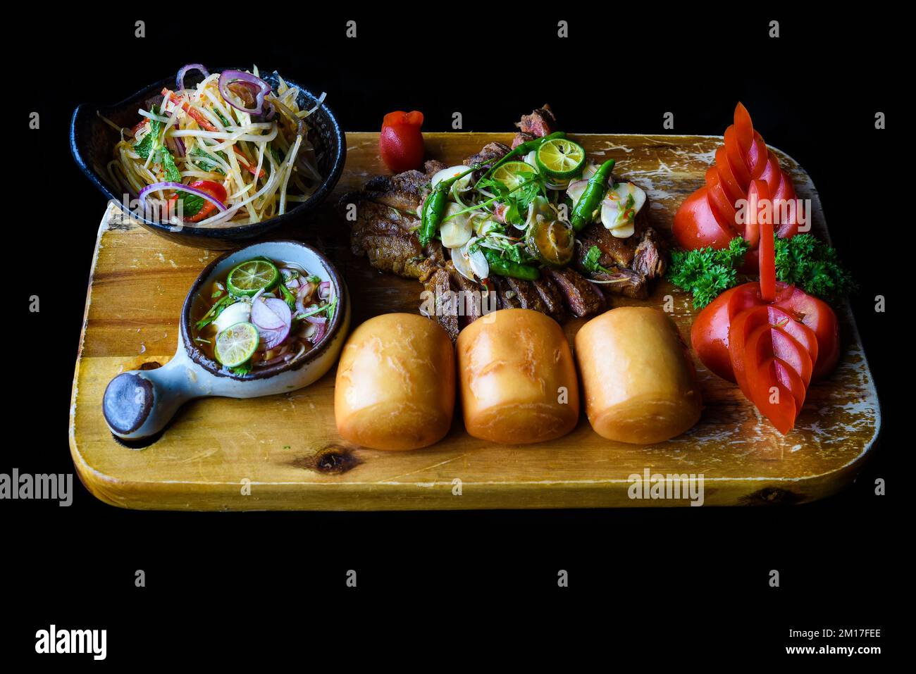 Grilled thai beef served with papaya salad, vietnamese buns and kumquat sauce top view Stock Photo