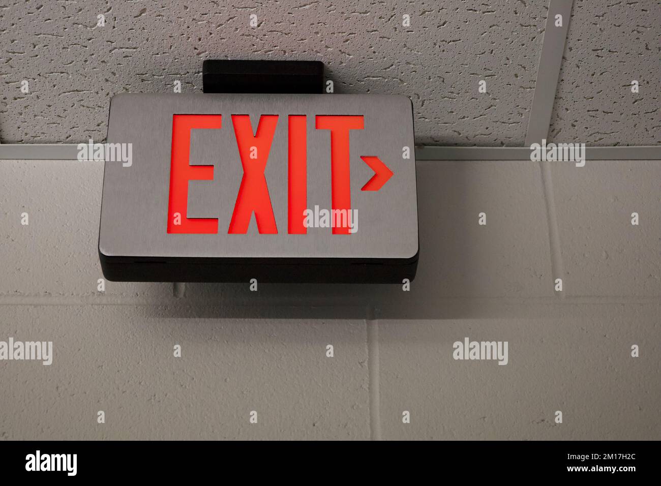 Exit sign in US school building with painted wall and drop down ceiling