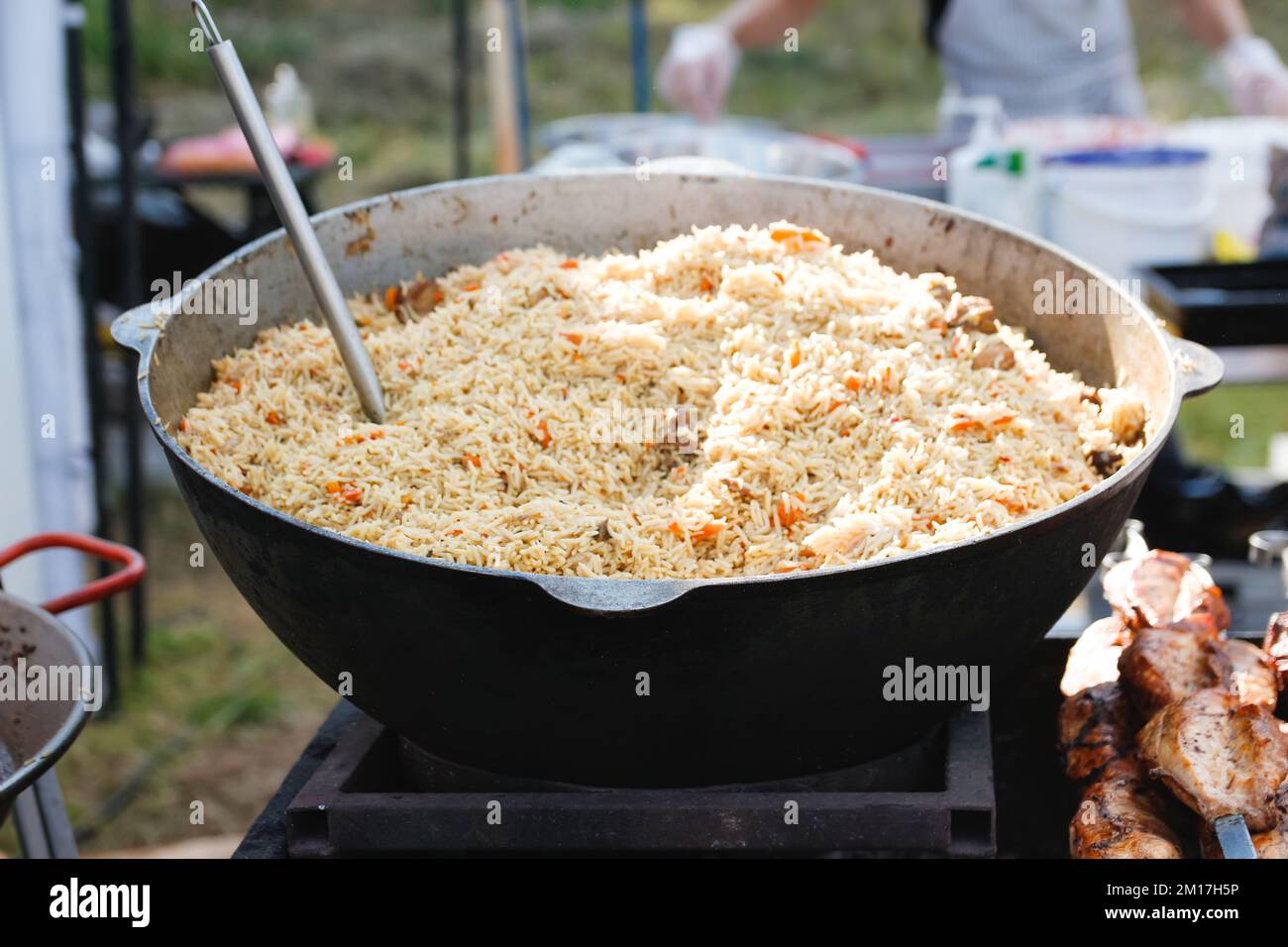 Defocus stirring the pilaf in a large bowl during cooking outdoors