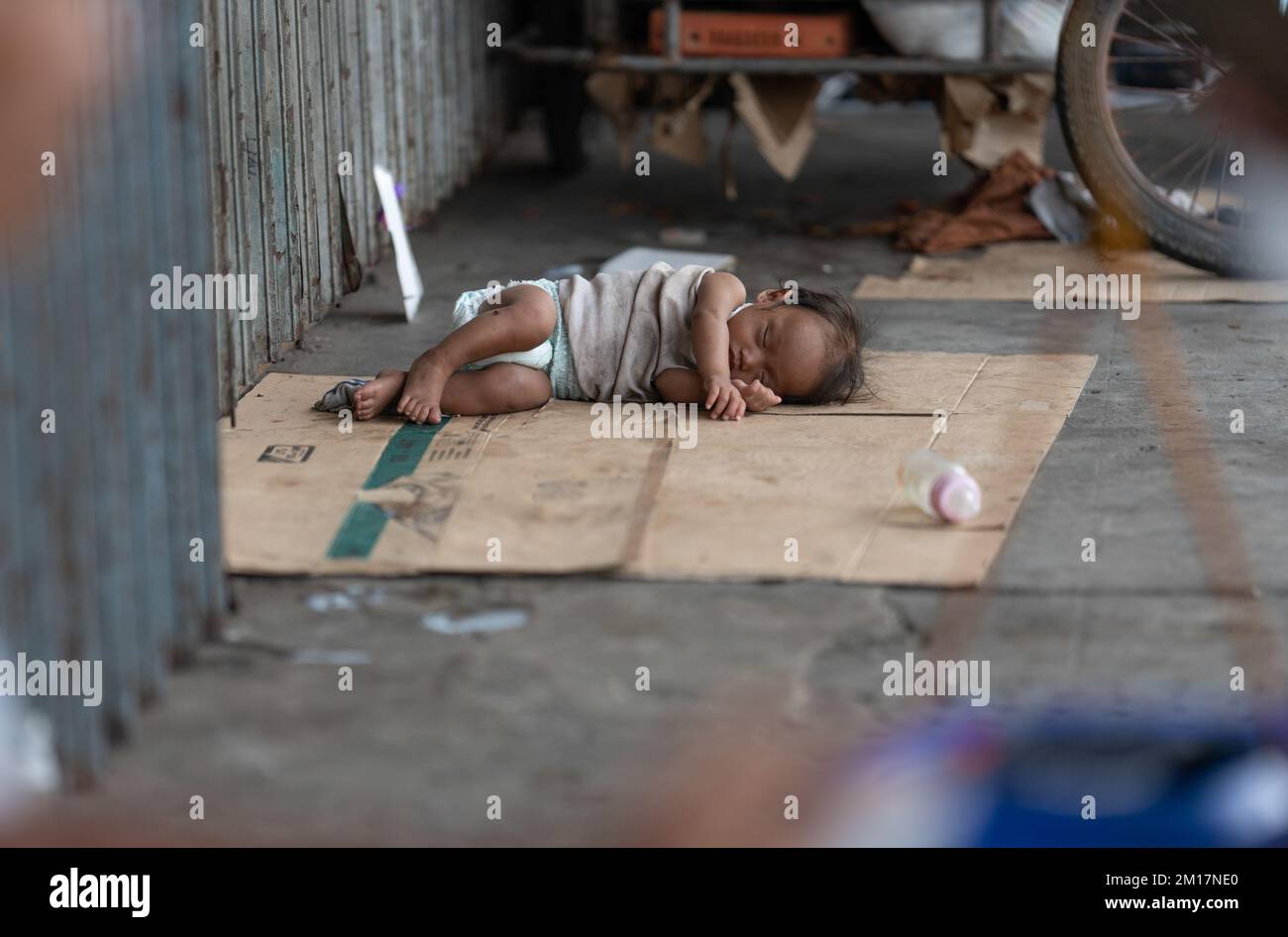 A small infant homeless street child, sleeping on a makeshift bed made of cardboard,Cebu City, Philippines Stock Photo