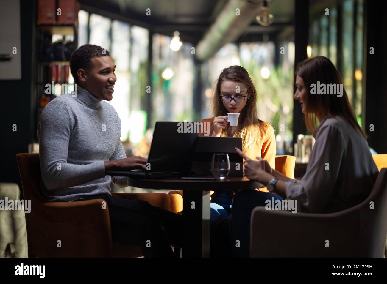 Three multiracial business colleagues having a meeting after work or ...