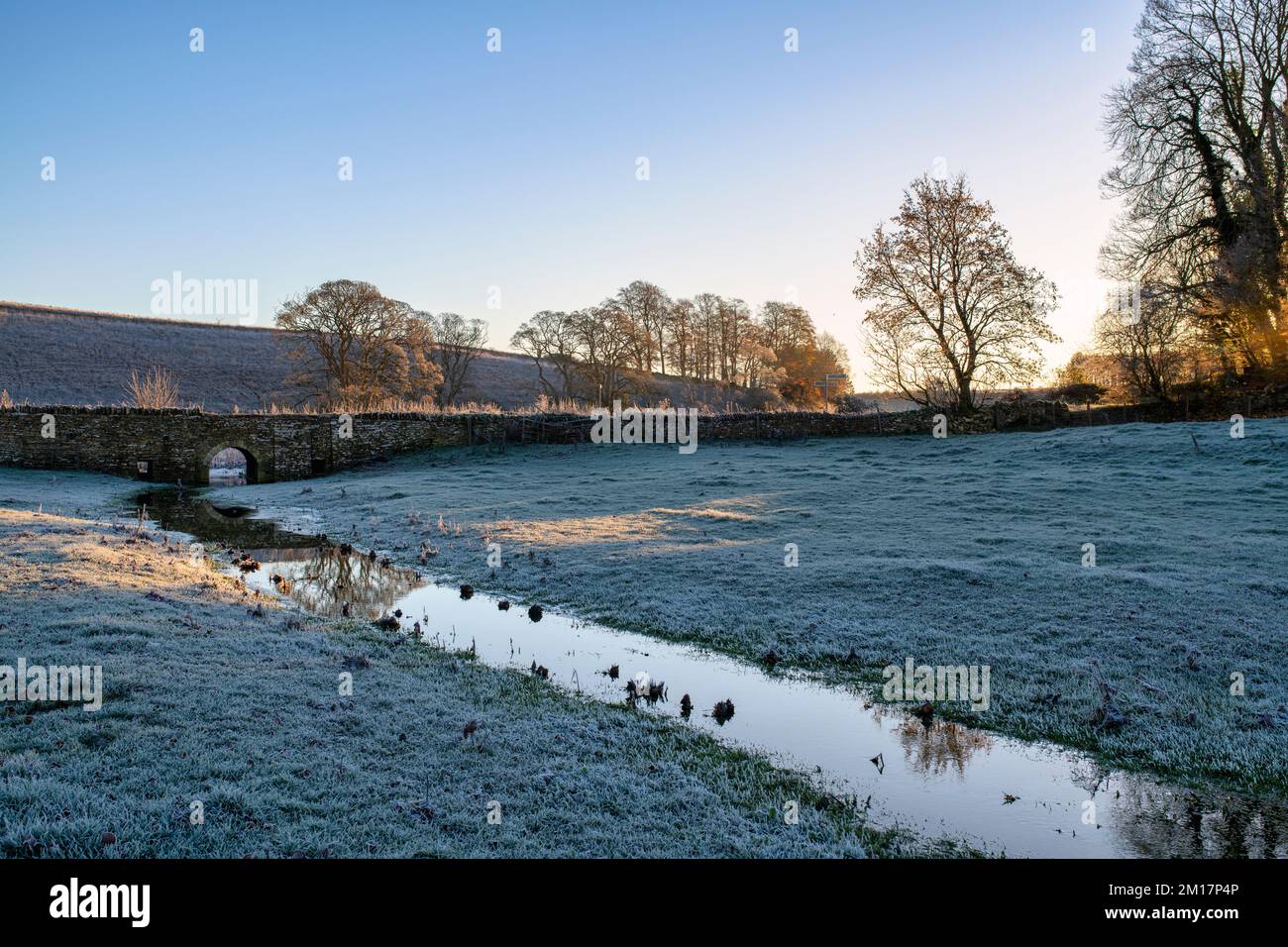 River Leach and stone bridge on the a frosty morning. Hatherop estate, Cotswolds, Gloucestershire, England Stock Photo