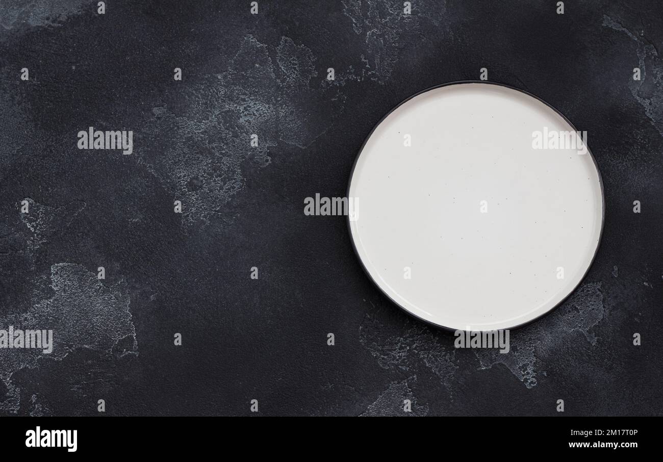 White plate on black textured background, top view, space Stock Photo