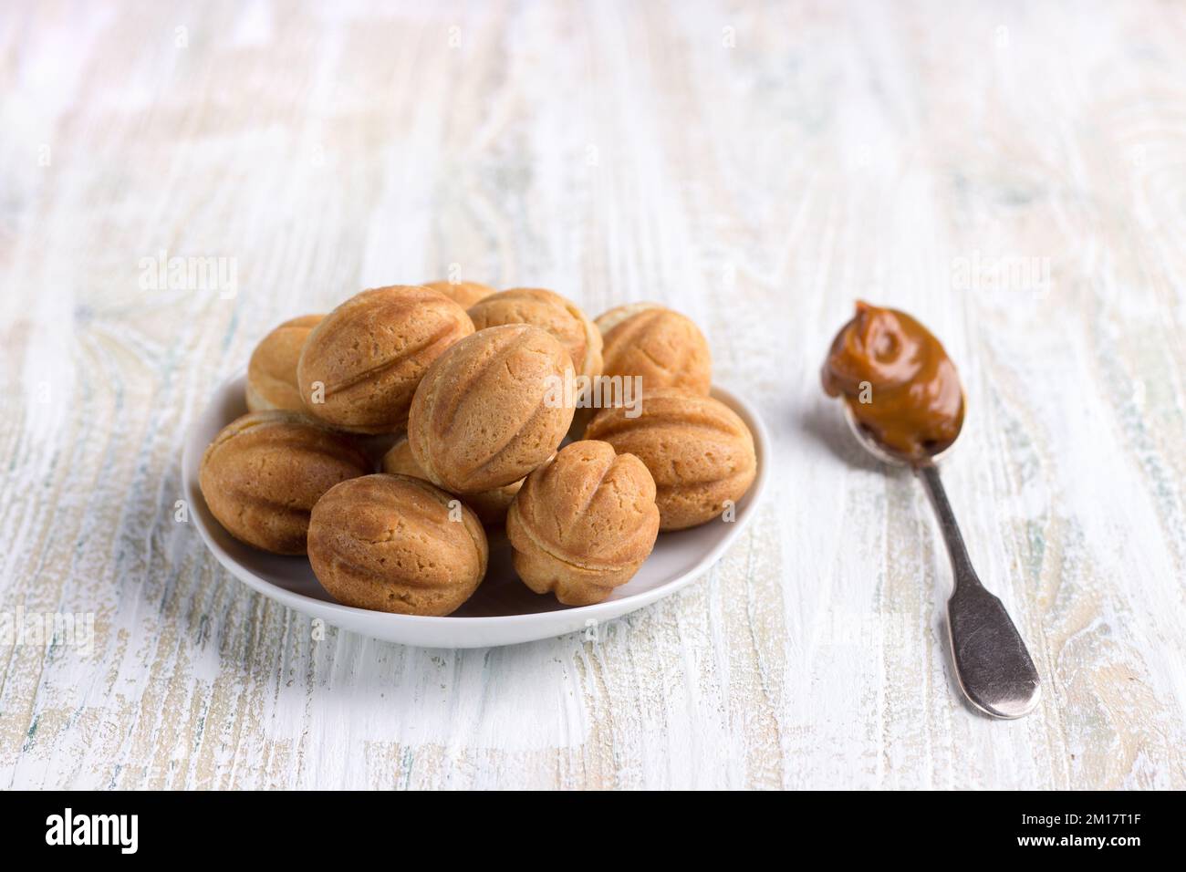 Traditional Russian homemade sweet pastries, shortbread nuts with boiled condensed milk on a wooden background Stock Photo