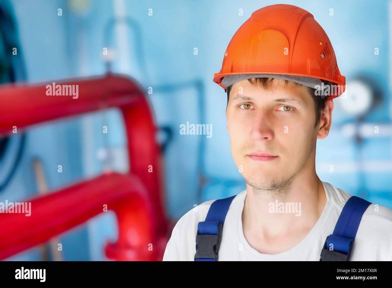 Man in construction helmet looks directly into cell inside room. Authentic portrait of real gas worker.. Stock Photo