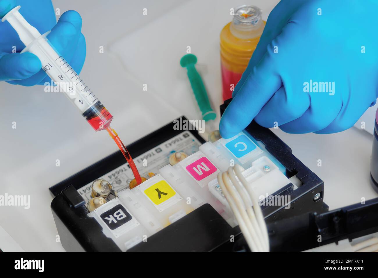 Printer maintenance. Master fills inkjet printer with ink or syringe