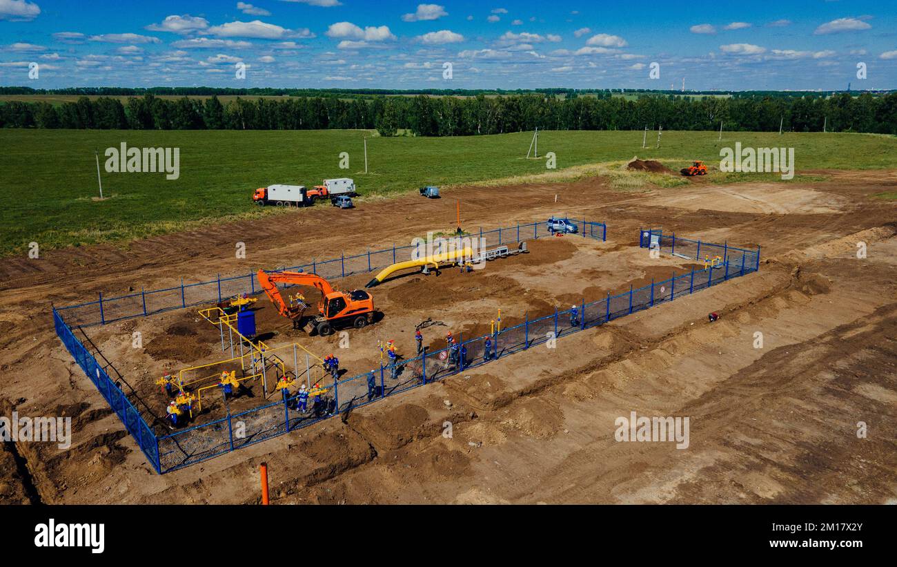 Aerial view excavator and construction workers working on construction site in open field. Pipe laying in trench for gasification. Top point of shooting. Repair and restoration of natural gas supply.. Stock Photo
