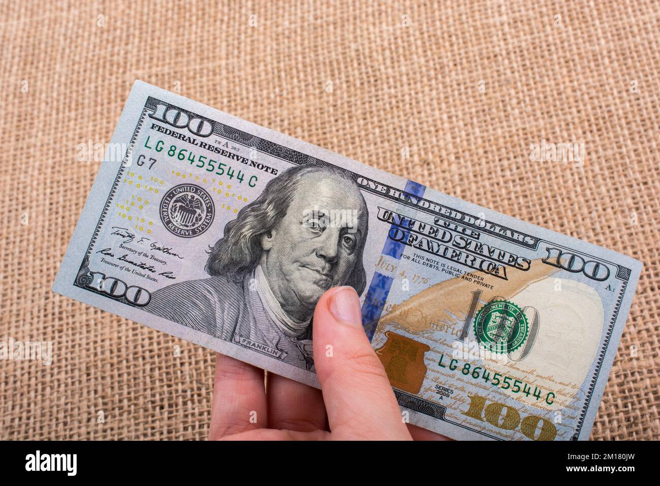 Hand holding banknote bundle of US dollar on a linen canvas background ...