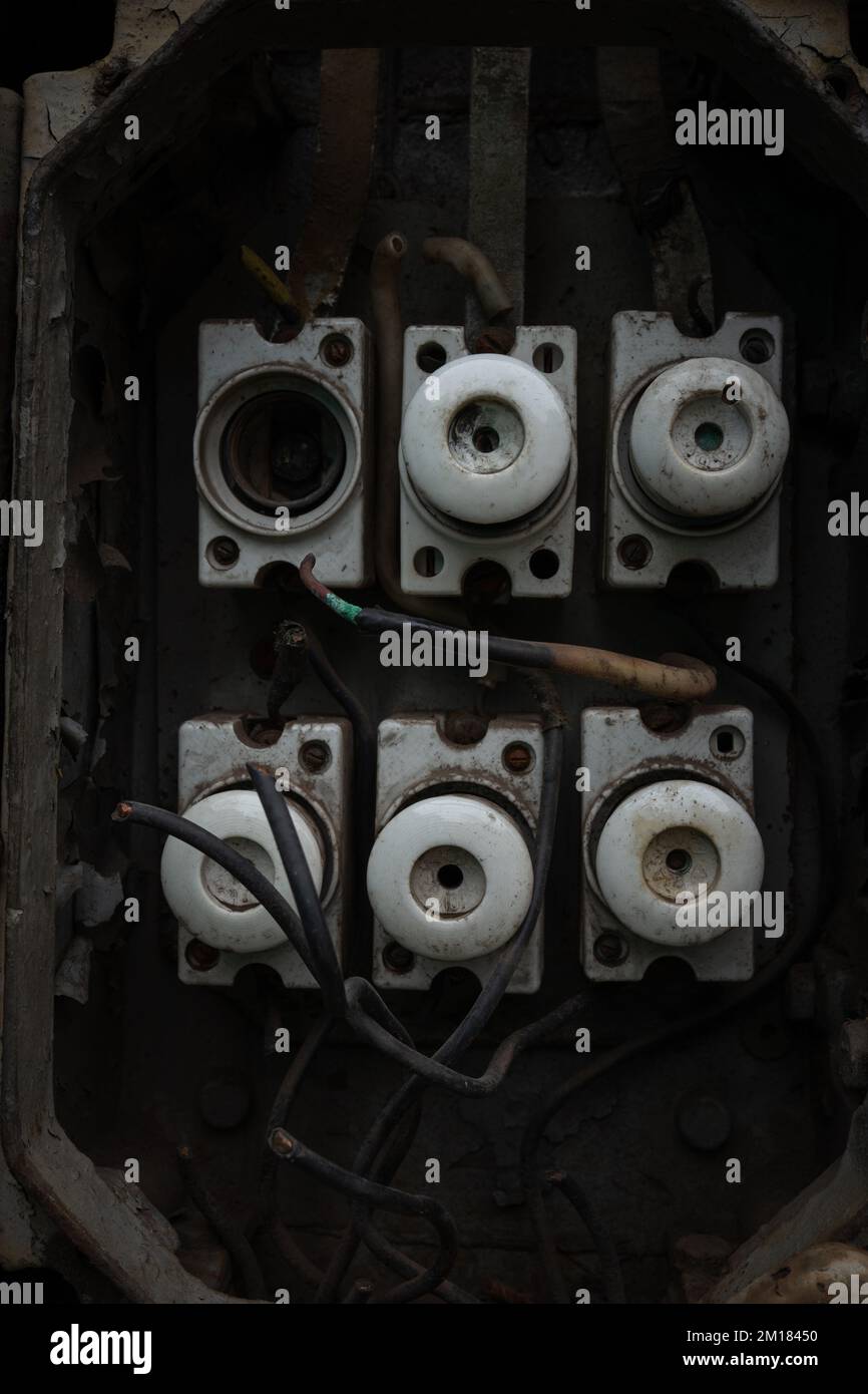 Old abandoned industrial electrical switchboard with heavy rust, broken covers and ceramic fuses Stock Photo