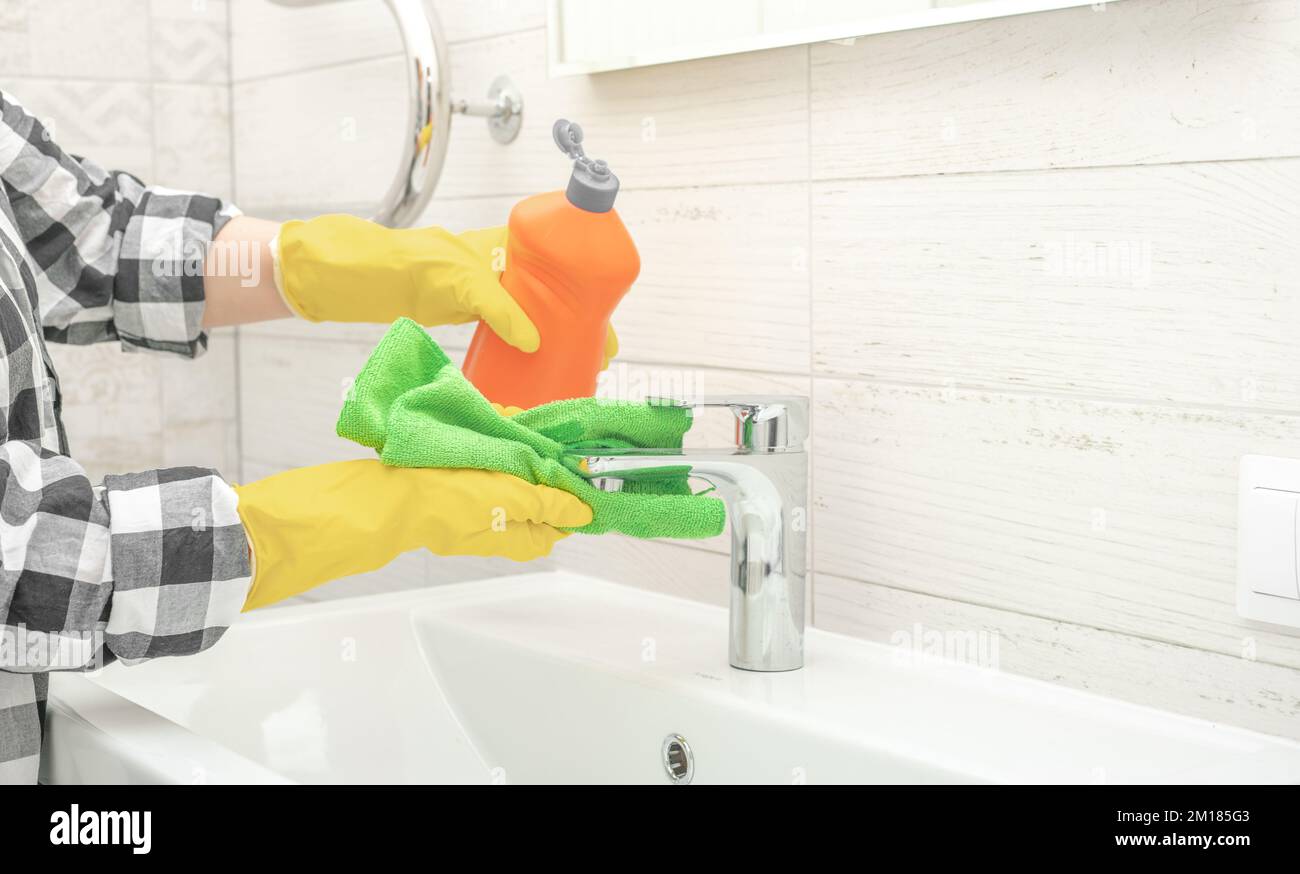 Cleaning service. cleaning tap faucet with detergent in bathroom. Man