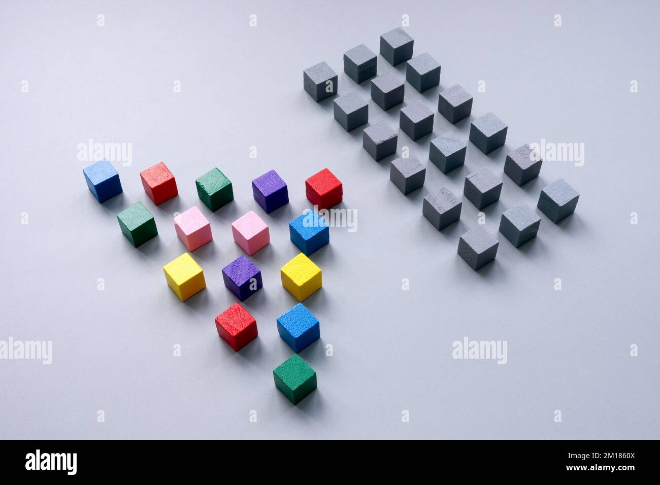 Multi-colored cubes are lined up opposite gray ones. Unity and a common struggle against obstacles. Stock Photo