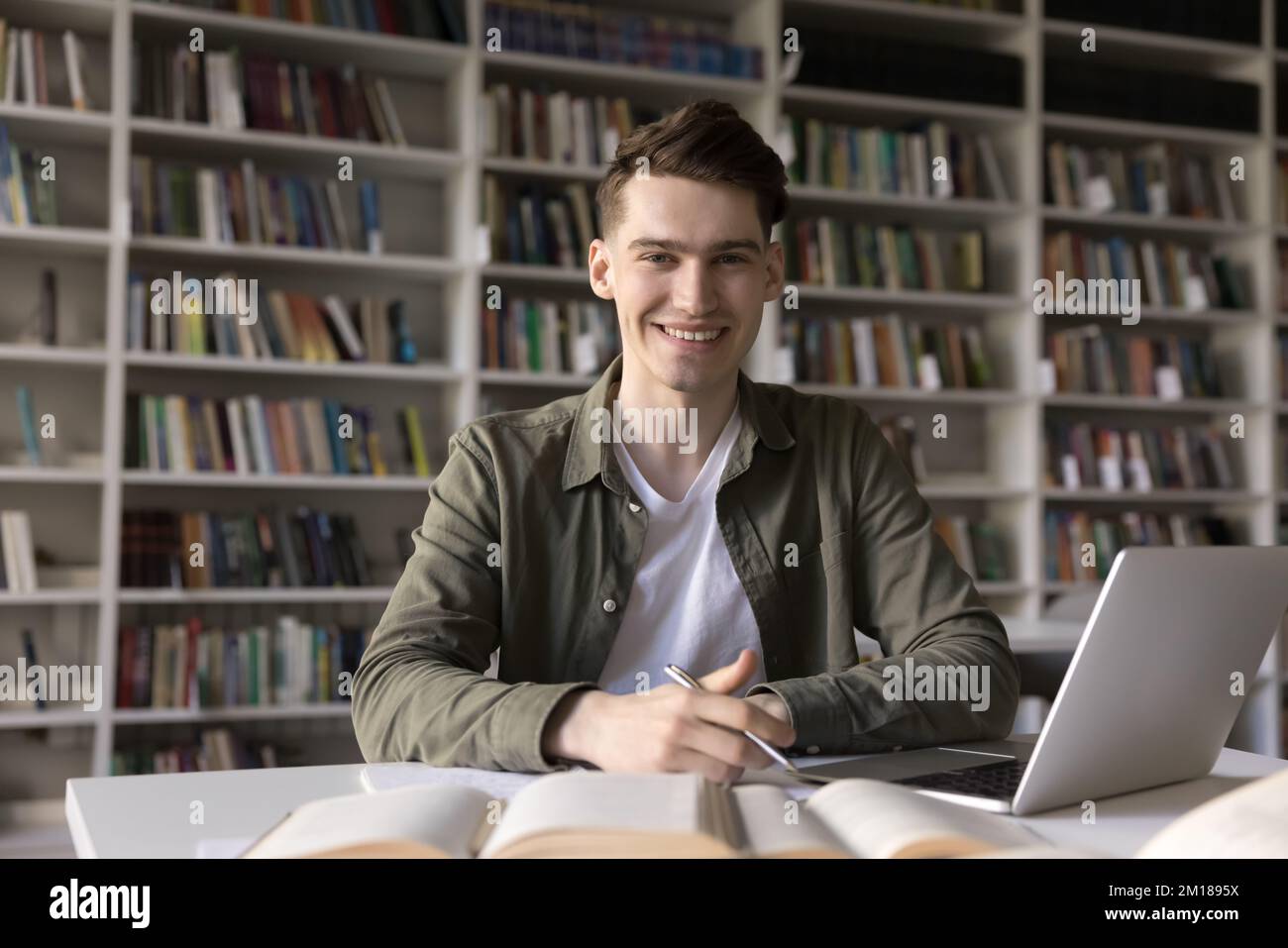 Happy successful college student guy working on article in library Stock Photo